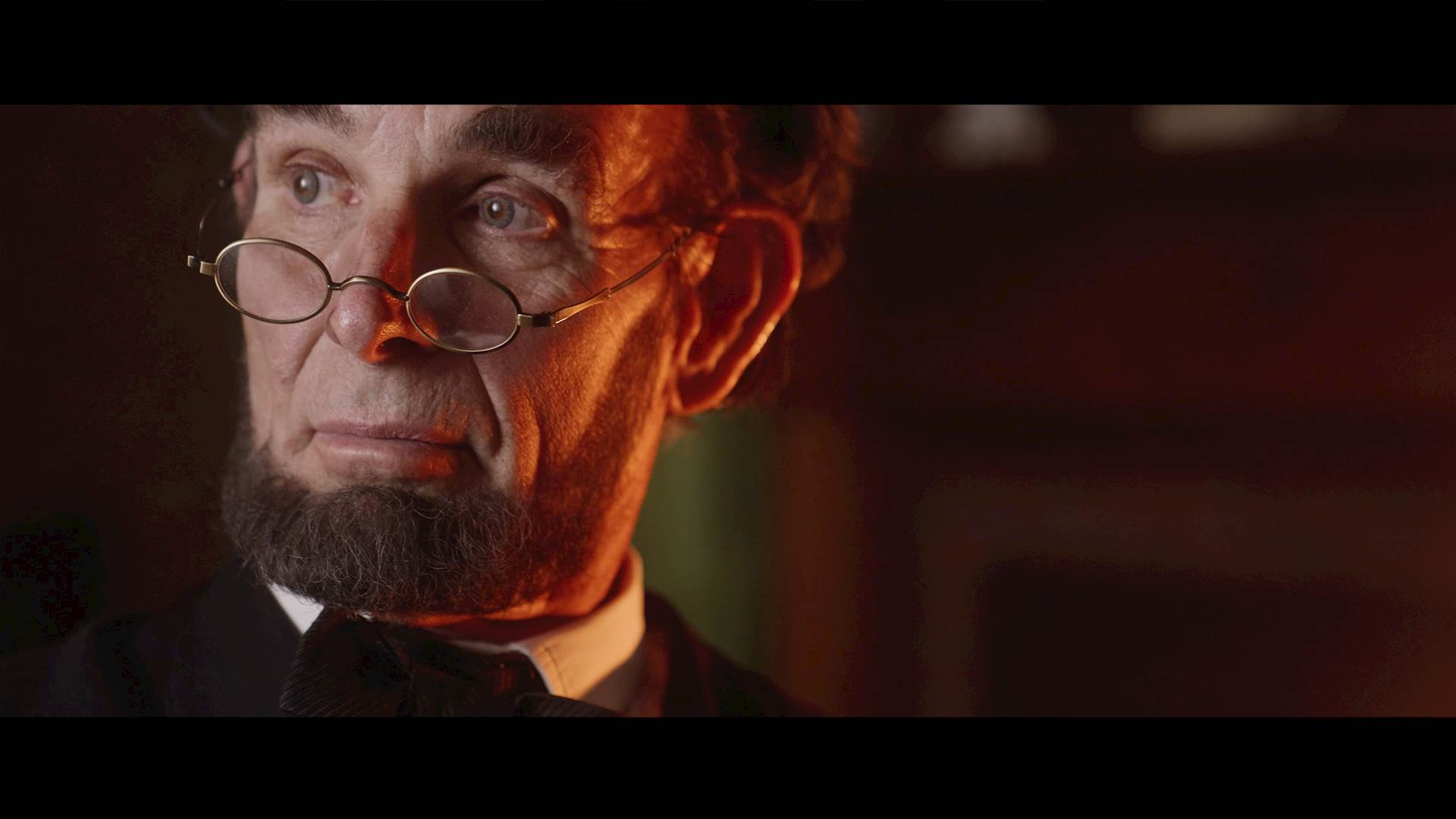 Lincoln, with his glasses at the tip of his nose, looks off into the light.